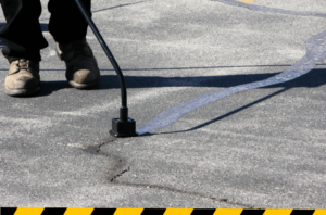 worker filling asphalt cracks